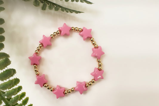 Pink star-shaped beaded bracelet on a white background with green leaves.