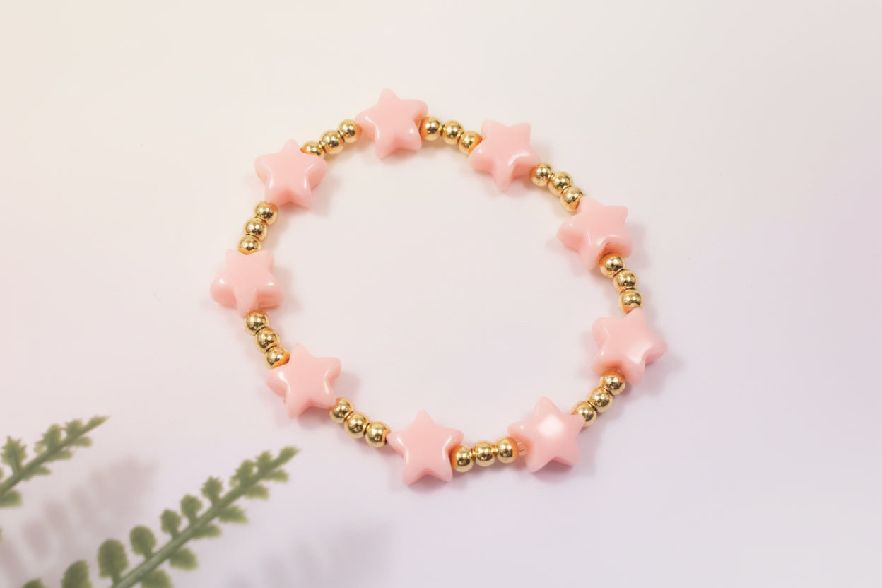 Bracelet with pink star-shaped beads and gold accents on a light background