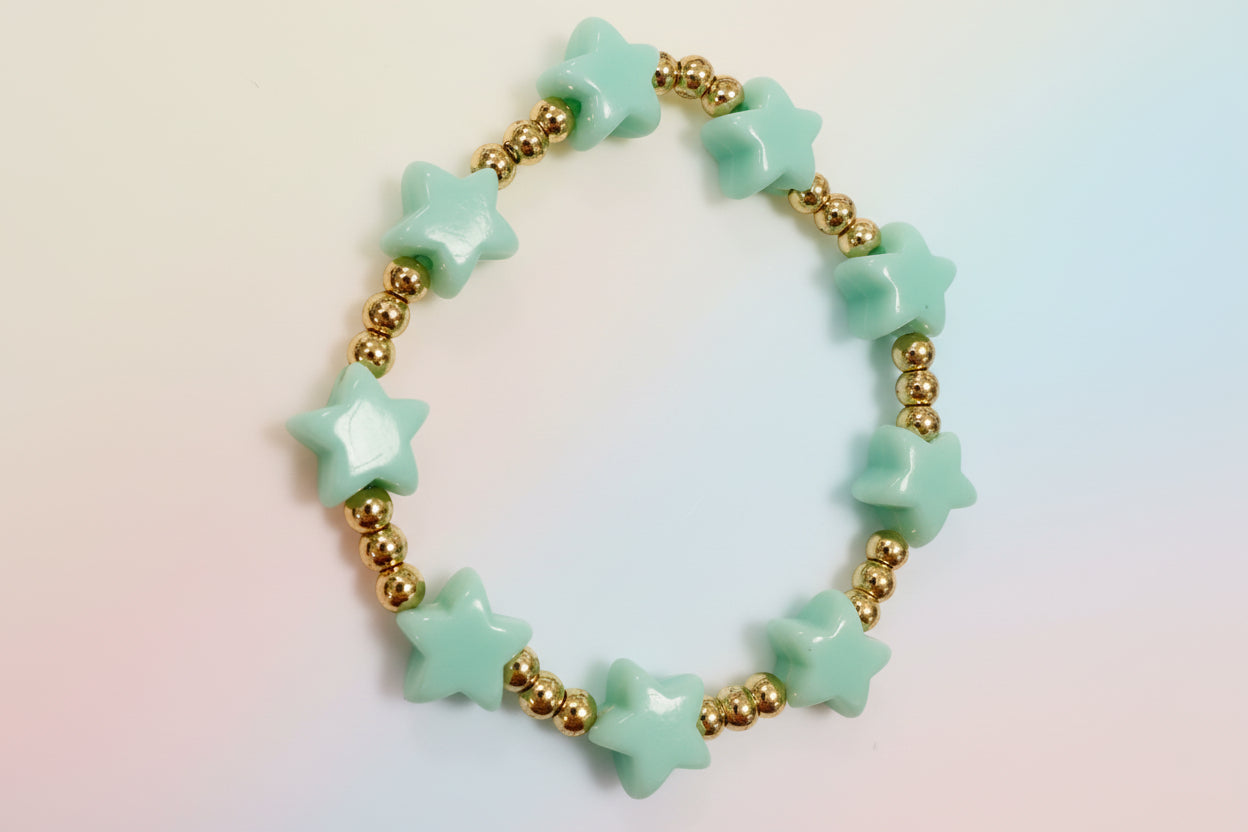 Bracelet with turquoise star-shaped beads and gold beads on a light background
