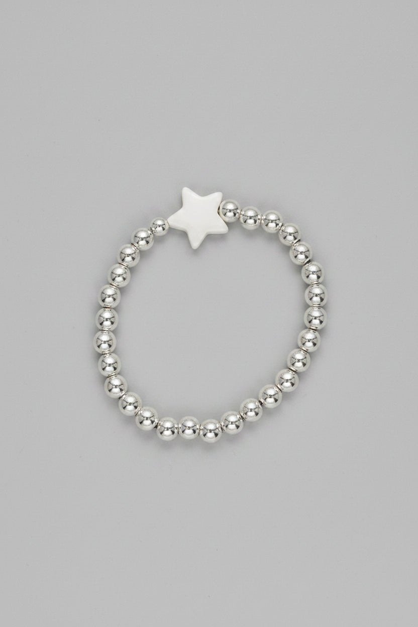 Silver beaded bracelet with a star charm on denim fabric