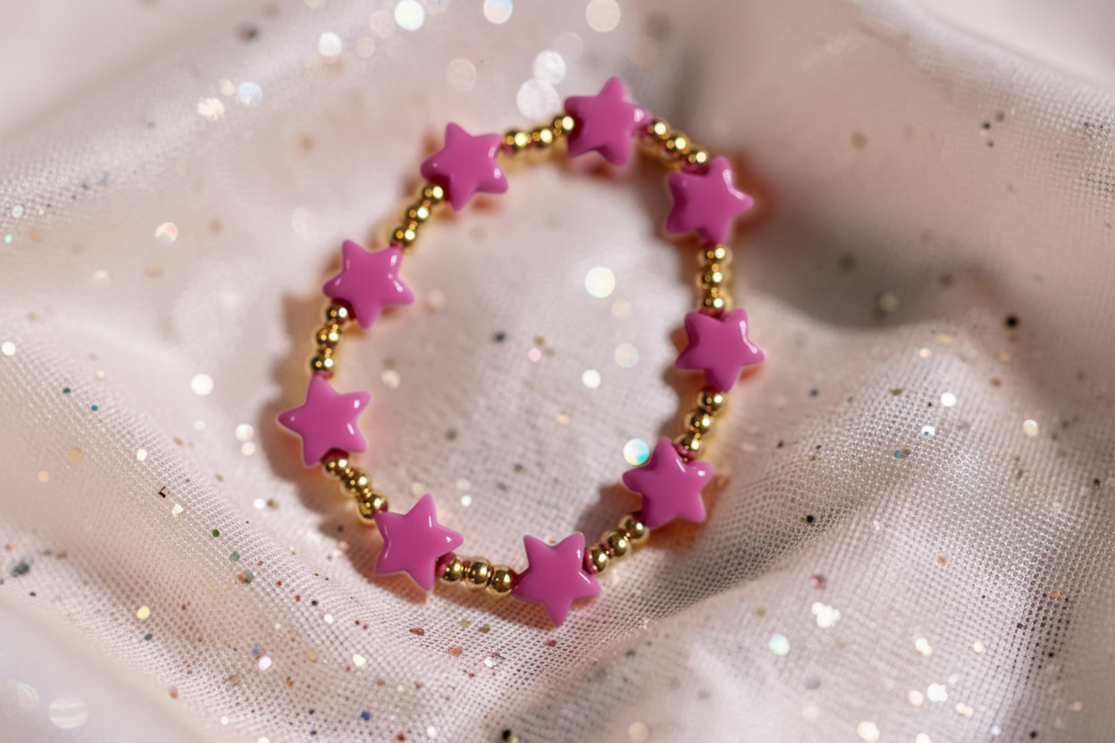 Bracelet with pink star-shaped beads on a glittery fabric background